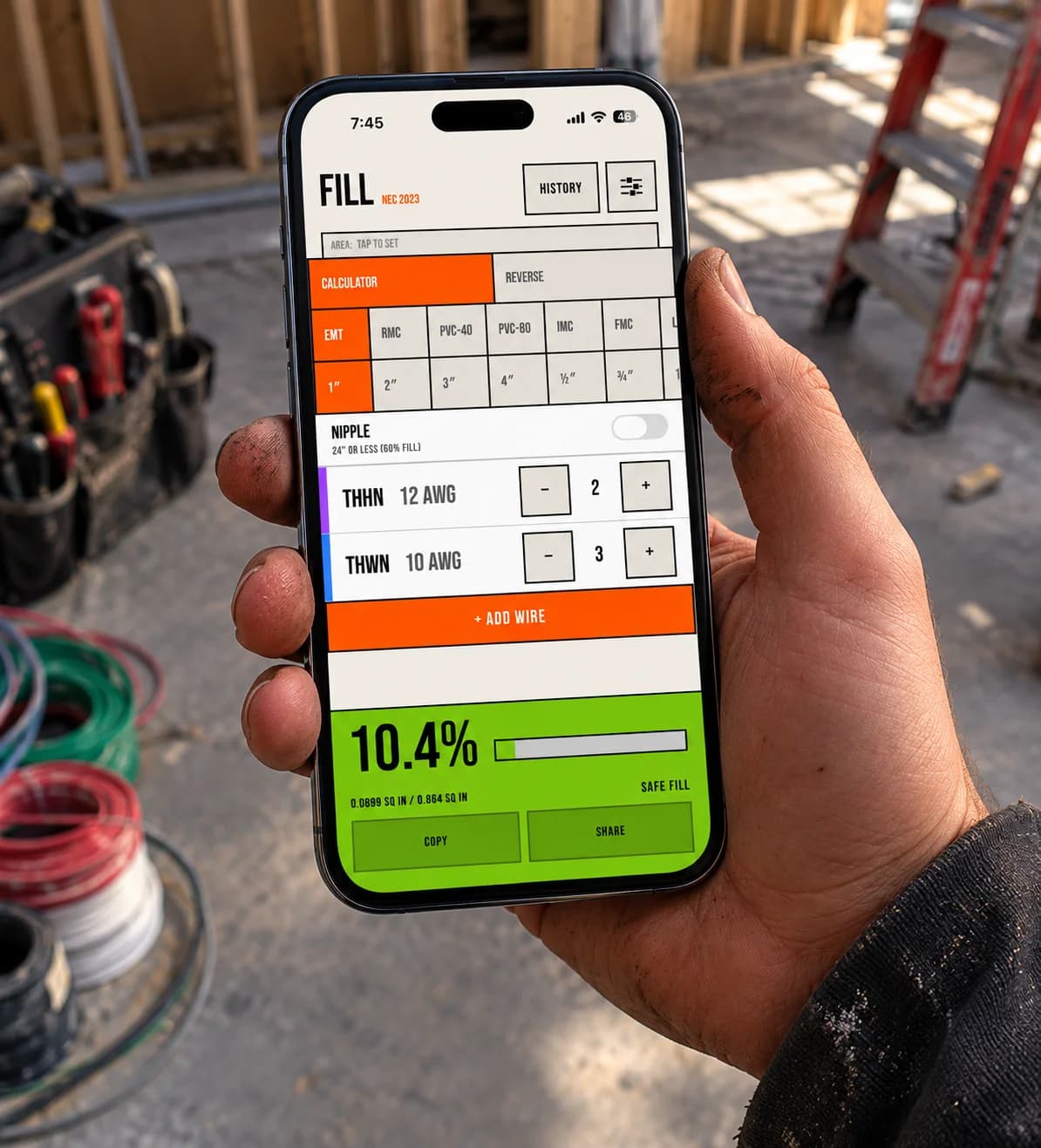 FILL in use on a jobsite, held one-handed by an electrician with wire spools and a tool bag in the background